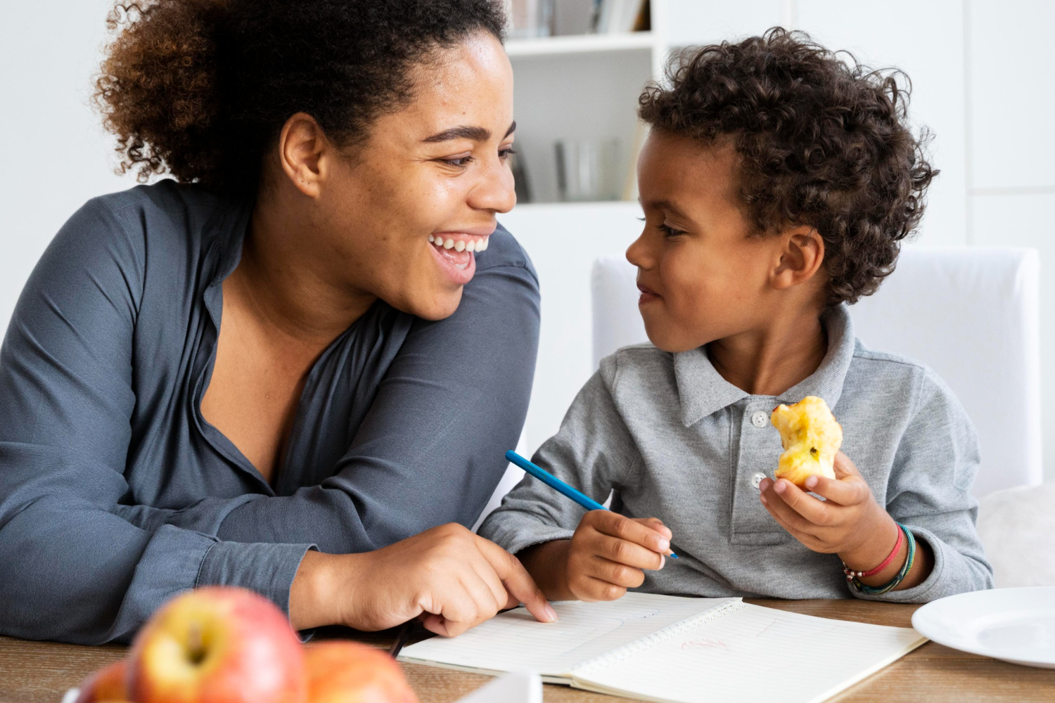 Smiling child interacting with a parent or therapist in a learning environment.
